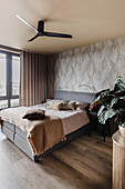 Modernes Schlafzimmer mit Blattmuster-Tapete und Deckenventilator
