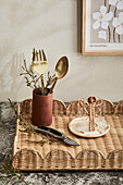 Rattan tray with gold-coloured cutlery and ceramic crockery