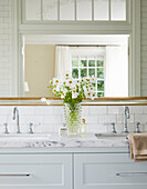 Marble washbasin with double washbasin and decorative glass vase with white flowers