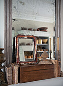 Antique mirror with candles and old books on a mantelpiece