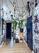 Hallway with botanical wallpaper, dark blue doors and hanging light bulbs