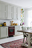 Country-style kitchen with red hob and adjoining dining area
