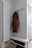 Entrance area with coat hooks and white bench with shoe rack