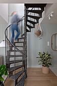 Modern metal spiral staircase in front of wood-panelled wall