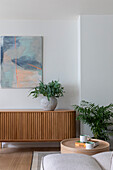 Modern living area with wooden sideboard, artwork and green plants