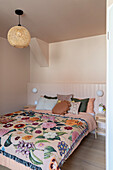 Bedroom with floral bedspread and woven ceiling light