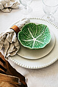 Table setting with green ceramic bowl in cabbage shape and linen napkin