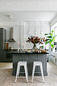 Grey and white kitchen with island, bar stools and autumn flower arrangement