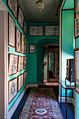 Hallway with turquoise-coloured walls, framed pictures and carpet runner