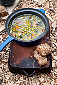 Stew with peas and vegetables in a blue cast iron pan, served outdoors