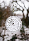 Ice decoration with crocheted doily on a branch in the conservatory