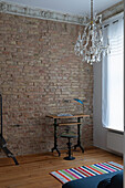Old building room with small desk, crystal chandelier and brick wall