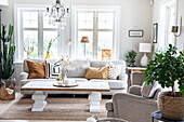 Bright living room with chandelier, various indoor plants and Scandinavian decor