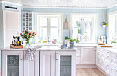 Bright country-style kitchen with blue-painted walls and white wooden cupboards