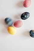 Colourfully painted Easter eggs, on a white surface, one in motion