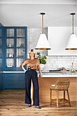 Woman laughing in modern kitchen with blue cupboards and tiled wall