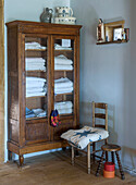 Antique wooden cabinet with glass front and stacked towels