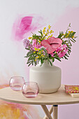 Bouquet with flamingo flower (Anthurium), mimosa and hyacinths in a white vase on a wooden table