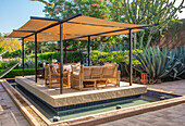 Sitzbereich mit Markise und Rattanmöbeln im marokkanischen Sukkulentengarten