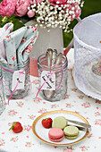 Summery table setting with macarons, strawberries, cutlery and napkins