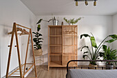 Minimalist bedroom with open wardrobe and indoor plants