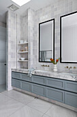 Modern bathroom with grey-blue commode, light grey tiles and large mirrors
