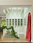 Winding staircase with plant decoration and red curtain in the bright hallway