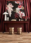 Wooden table with abstract painting in front of a red curtain