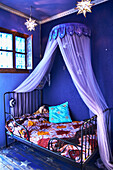 Metal bed and canopy in blue-painted children's room