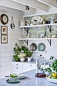 Bright kitchen with open shelving, marble counter and various plants