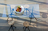 Modern glass table with wooden stools and fruit bowl