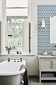 Historic bathroom with blue patterned tiles and free-standing bathtub