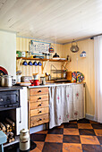 Small country house kitchen with wooden fronts and checkered wooden floor
