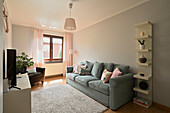 Living room with blue-grey couch and pastel-coloured cushions