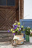 Spring bouquet with violets and twigs in a dotted basket in front of a wooden door