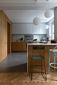 Kitchen with modern wooden fronts and green metal bar stool