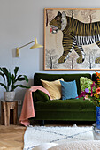 Green velvet sofa with colourful cushions and tiger picture on the wall