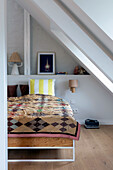 Bed in the loft with patterned bedspread and colourful pillows