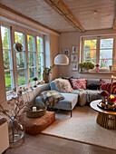 Living room with window front, corner sofa and autumnal decoration