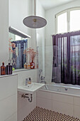 Bright bathroom with patterned floor tiles and purple shower curtain