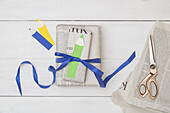 Back-to-school gift in newspaper with blue ribbon next to scissors