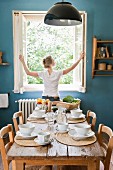 Lunch table in the kitchen and a woman closing the window