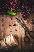 Lilacs, scissors and twine reel on wood