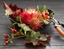 Dish of autumn flowers, rose hips and leaves