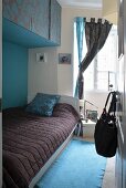 View into colour-coordinated bedroom with single bed below wall-mounted cupboards
