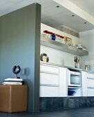 Simple, modern kitchen counter in niche and contemporary metal sculpture against grey partition wall