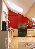 Wohnküche im ausgebauten Dach mit roten Oberschränken und transparenten Acryl-Stühlen