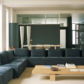 Dunkle Sofalandschaft und schwarze Einbauwand kombiniert mit hellen Holztischen in modernem Wohnraum im Loftstil