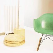 50er Jahre Sessel mit grünem Schalensitz und Fuss einer 70er Jahre Bogenlampe hinter geflochtenen Bodenkissen