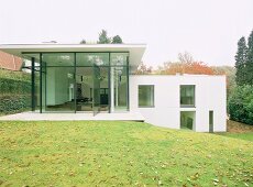 Zeitgenössisches Wohnhaus im Stil der Moderne mit aufgeglaster Fassade und versetzten Ebenen am Hang